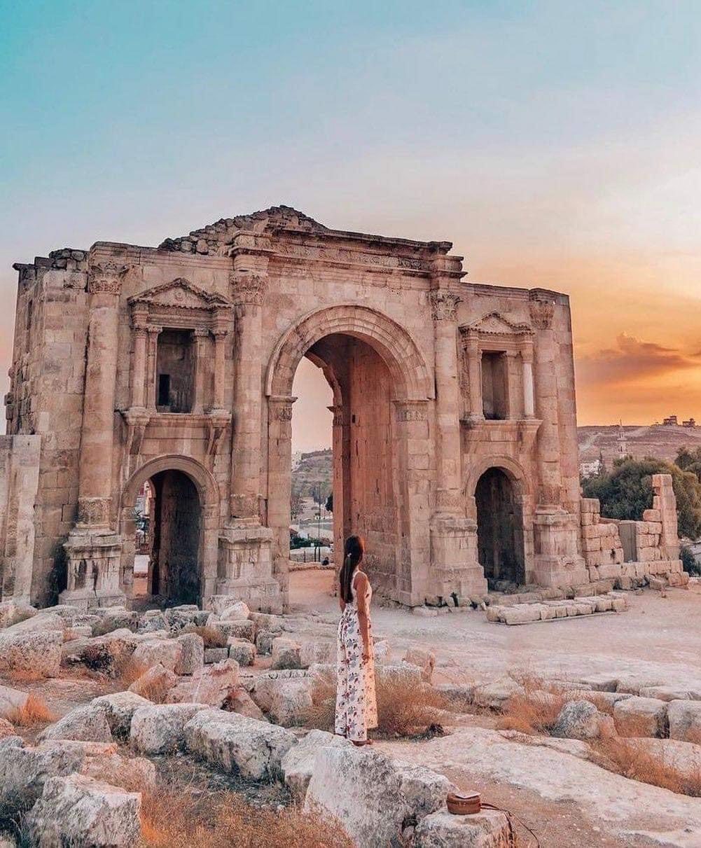 Arch of Hadrian in Jerash, Jordan, a grand Roman triumphal arch with a person viewing it at sunset.