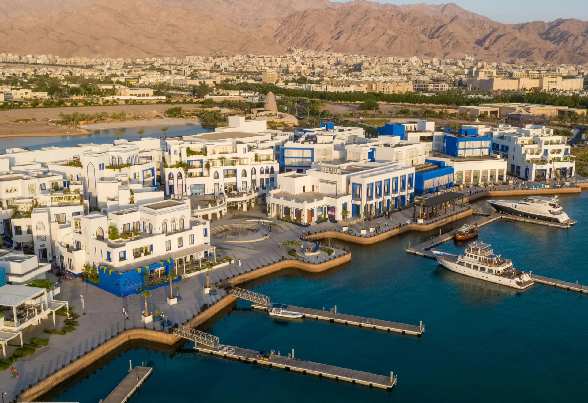 Ayla Oasis Marina Village in Aqaba with waterfront buildings, yachts and mountains